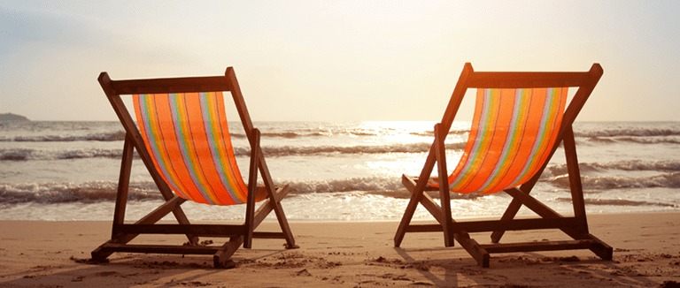 Banner Image of Two Empty Deckchairs on a Beach at Sunset